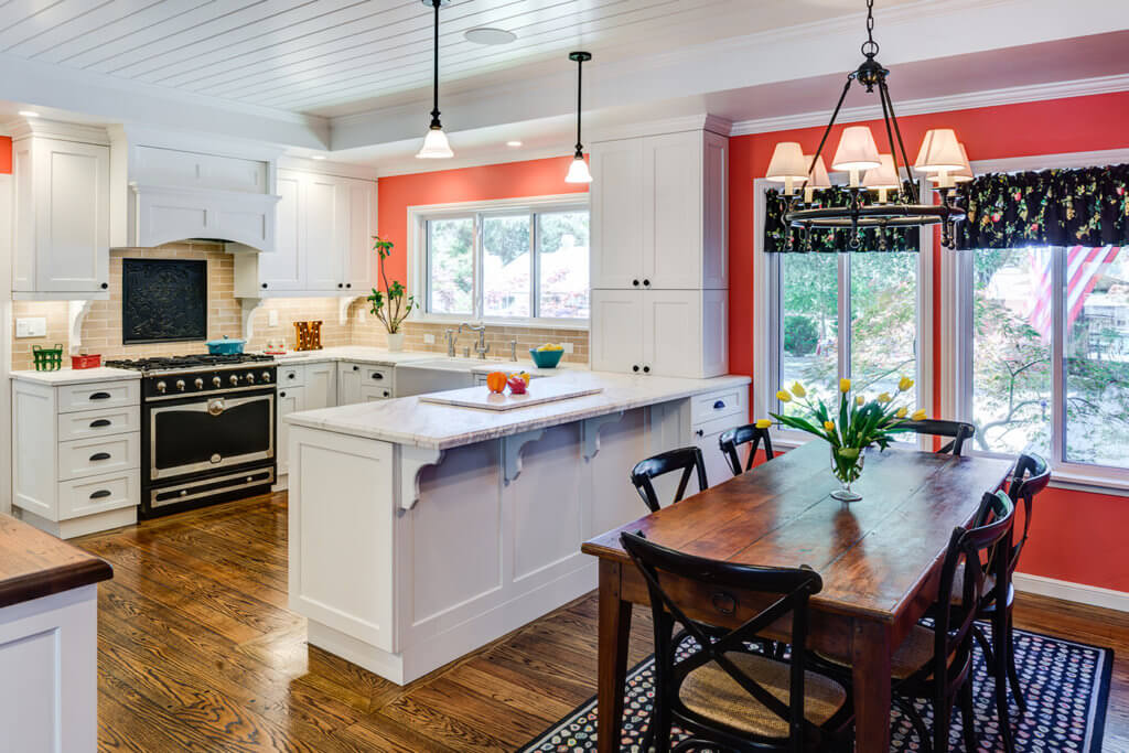 A warm and welcoming kitchen remodel that has white cupboards, a red accent wall and barn inspired decor.