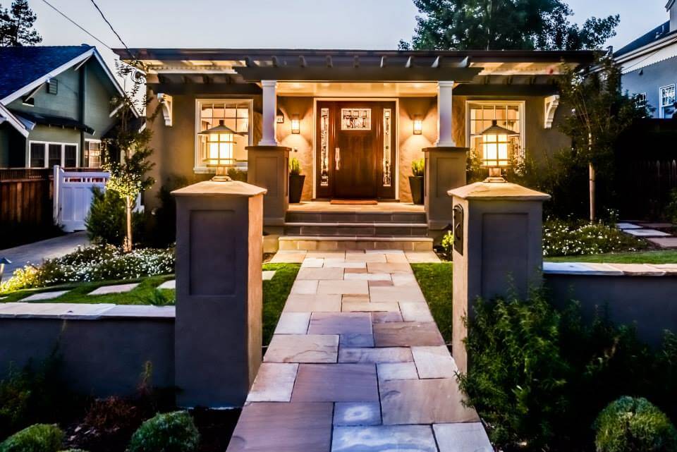 An exterior shot of a home with a large porch and interesting lighting sconces. 