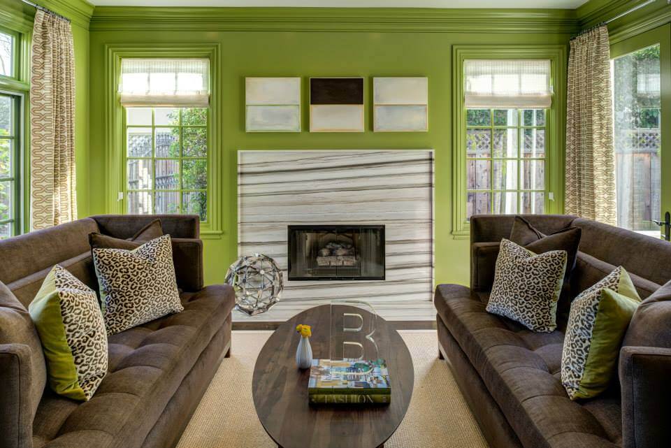 An interior shot from a design-build company showing off a living room painted green with lots of windows.