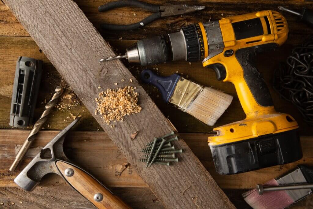 Tools used for home renovation. A hammer, screws and power drill.
